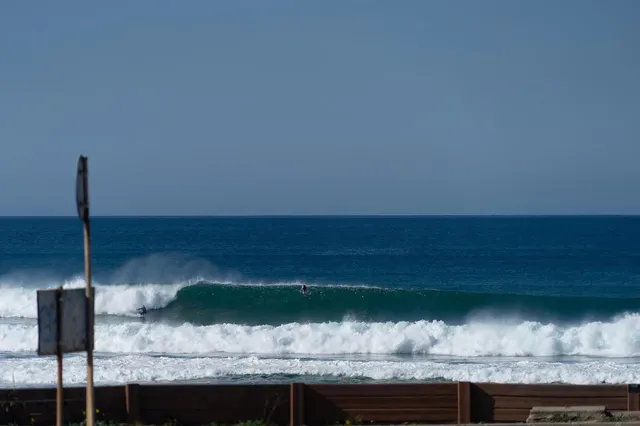 Uma série de ondas a quebrar na costa, com um praticante na água.