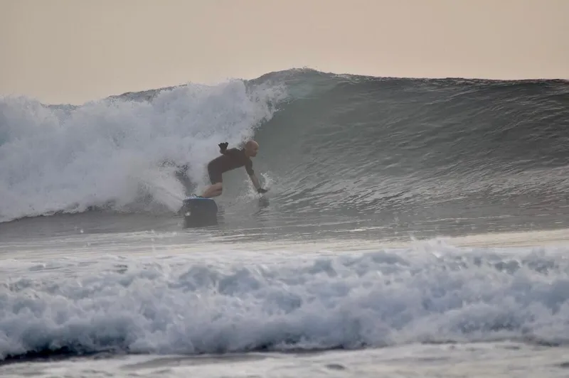 Surfista do clube numa onda, com espuma em primeiro plano.
